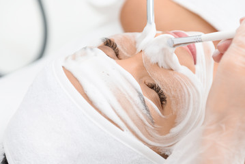Pretty girl receiving facial foam procedure at spa