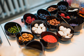 Nuts, berries and marshmallow lie in black bowls