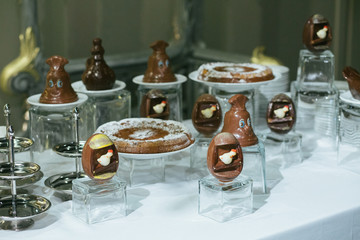 Chocolate eggs and bells stand on the glasses on a buffet