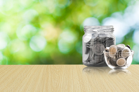 coins in a glass jar on Wood floor ,savings coins - Investment And Interest Concept saving money concept, growing money on piggy bank. isolated on green background