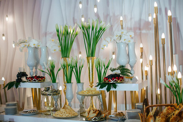 White callas and orchids stand on the table full of berries and