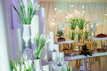 White callas stand on high tubes behind a buffet