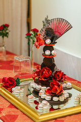 Red poppies lie on the mirror tray fool of macaroons