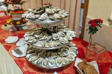 Tasty mussels lie on the tired tray on red buffet