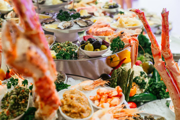 Plates with olives and salads stand on the table full of sea pro