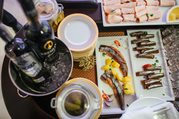 Cut sprats and sardines lie on square white dishes behind the pa