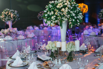 Huge bouquet of white tulips stand in high thin vase on a dinner