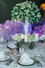 White festive served dinner table decorated with white bouquet o