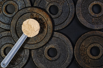 Scoop of whey protein on black background. Top view