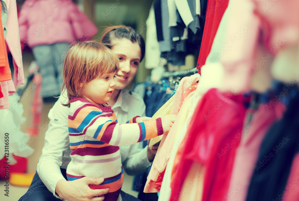 Poster   woman and child chooses wear at shop