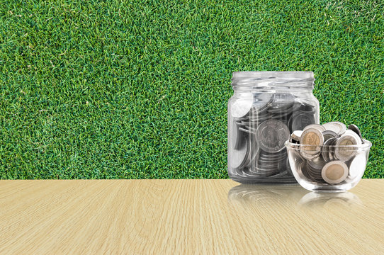coins in a glass jar on Wood floor ,savings coins - Investment And Interest Concept saving money concept, growing money on piggy bank. isolated on grass background