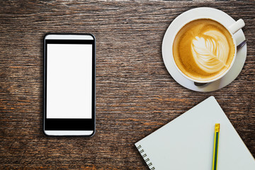 above coffee notebook with phone on wood table texture
