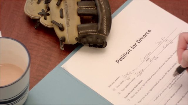 Woman signs divorce papers and places wedding ring on them