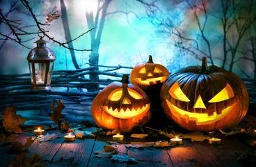 Fotobehang Halloween pumpkins on wood in front of nightly spooky forest background © Alexander Raths