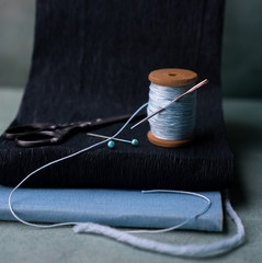 still life. an old reel of thread with a needle, pins, scissors. close-up.