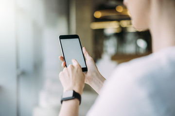 Mock up.Women's hands with cellphone.Girl presses finger on blank screen of smartphone.In female hand smartwatch.Student using gadget.Space for text.Selective focus,blurred foreground and background.