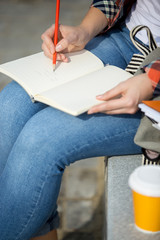 Student lady writing in an open notebook with a pencil. Back to school concept photo, closesup,...