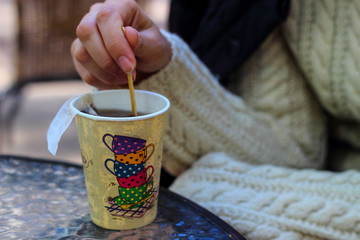 Fototapeta na wymiar Paper cup with painted colorful cups of tea in hand