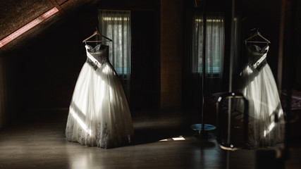 Wedding dress hanging on a hanger in the dark