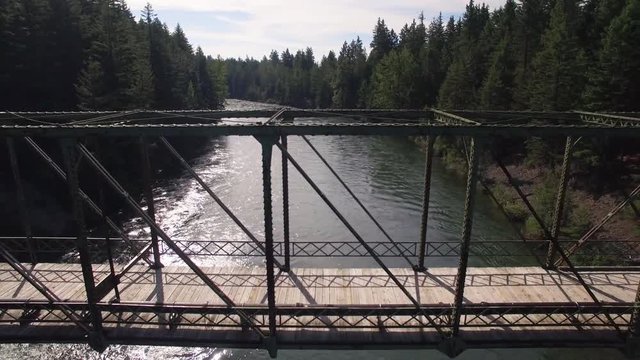 Aerial Nature Background of Rusty Footbridge Parallaxing with River in Mountain Forest
