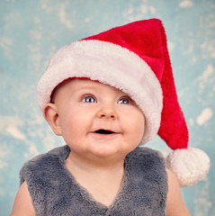 Baby mit Weihnachtsmütze und strahlenden Augen