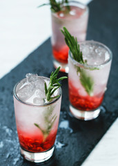 Close-up shot of refreshing berry cocktails with ice and rosemary