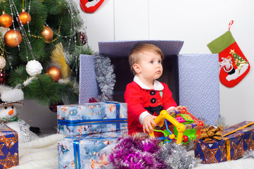 Cute little girl in Santa's suit near a Christmas tree