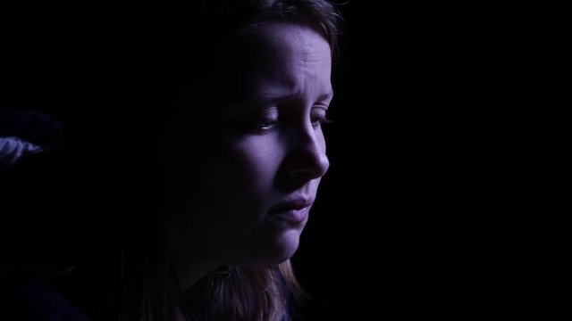 Depressed teen girl is crying in the dark. 4K UHD.