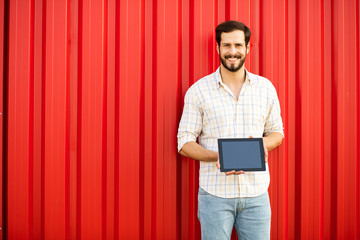 handsome man presenting tablet on red background