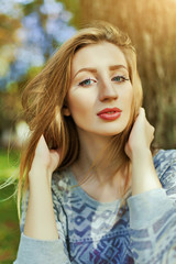 Naklejka premium Portrait of a young girl with blue eyes who is sitting in the park