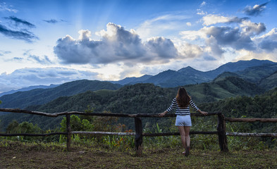 Young Woman standing alone outdoor with wild forest mountains on background