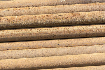 Old, rusty, dirty pipes are piled horizontally