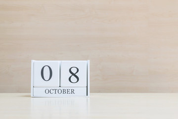 Closeup surface white wooden calendar with black 8 october word on blurred brown wood desk and wood...