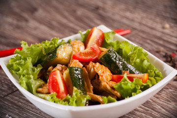 Spicy salad with chili cucumbers in a white plate on a wooden ba