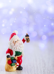 Merry christmas card with Santa Claus figurine. Lights background with space for text. Winter holidays. Xmas theme