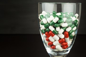 Glass of pills vitamins. Drugs in a glass container on a black background. Nutritional supplements for athletes. Diet concept.
