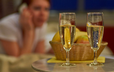 Obraz premium Two glasses of sparkling wine in hotel room with woman in backgr
