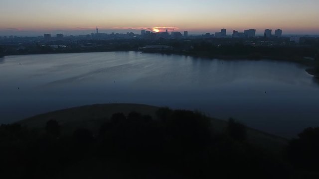 Aerial view flying towards Edgbaston reservoir at sunrise, Birmingham city centre in the distance.
