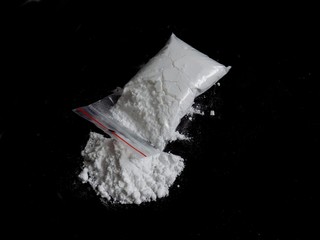 Cocaine drug powder in bag and cocaine powder pile on black background