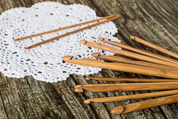 Wooden hooks for knitting.   Wooden hooks for knitting and round knitted a doily on an old wooden table.