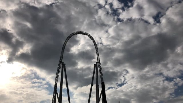 People ride a giant roller coaster - silhouette against a sky 4K