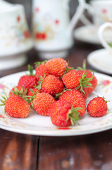 Mature, appetizing strawberries scattered on the white plate.