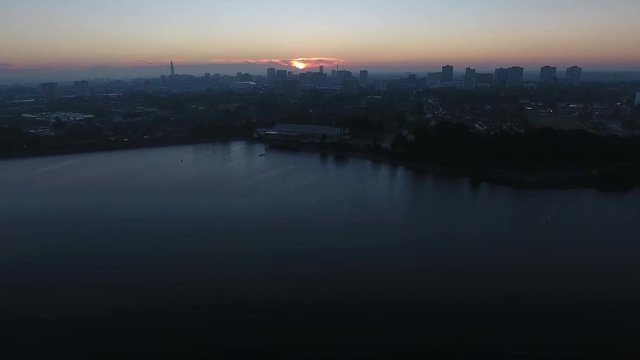 Aerial view rising up over Edgbaston reservoir with Birmingham city centre in the distance.