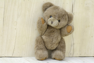 Brown teddy bear standing on the wooden floor.