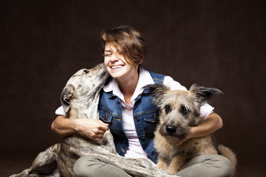 Beautiful young woman with two funny dogs on a dark background.