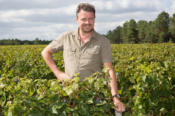 Middle aged winemaker in vineyard with arms crossed
