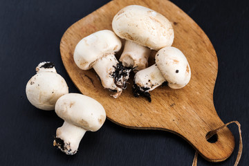 dirty champignon mushroom over wooden cutting board