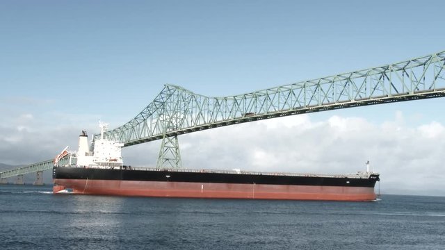 Large freighter ship traveling under bridge in Astoria, Oregon and into harbor.