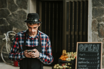 grocer with mobile phone at the entrance of their trade