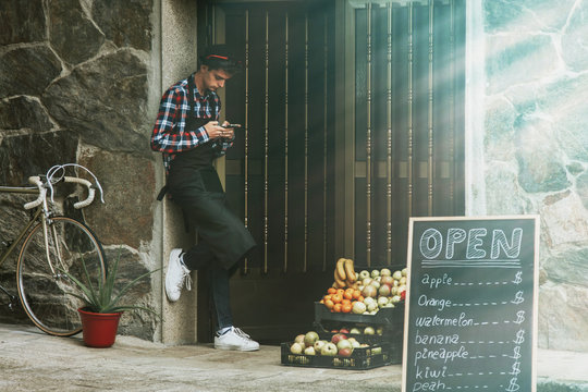 grocer with mobile phone at the entrance of their trade